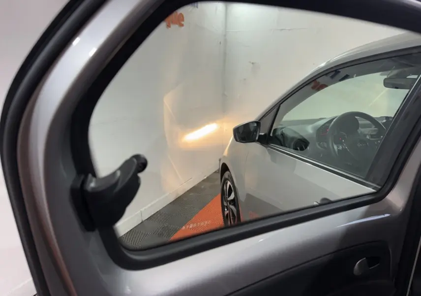 Vue depuis l'intérieur côté arrière droit, montrant la portière et le profil avant gris foncé du Volkswagen Up 2022.