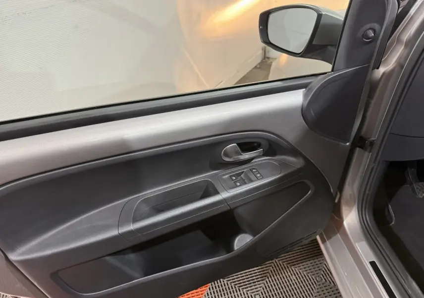 Intérieur de la porte avant gauche gris foncé du Volkswagen UP 2022 avec commandes de vitres et poignée métallique.