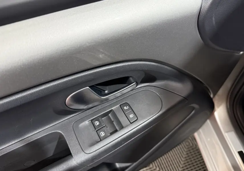 Poignée intérieure et commandes de vitres côté conducteur d'une Volkswagen Up gris foncé, vue rapprochée.