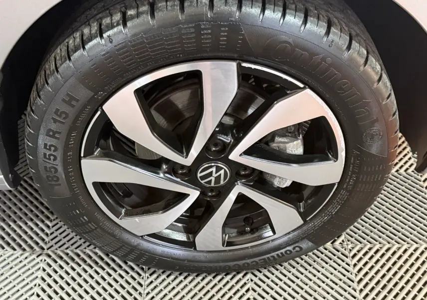 Gros plan sur la roue avant droite d'une Volkswagen Up gris foncé avec jante alliage noire et argentée au design moderne.