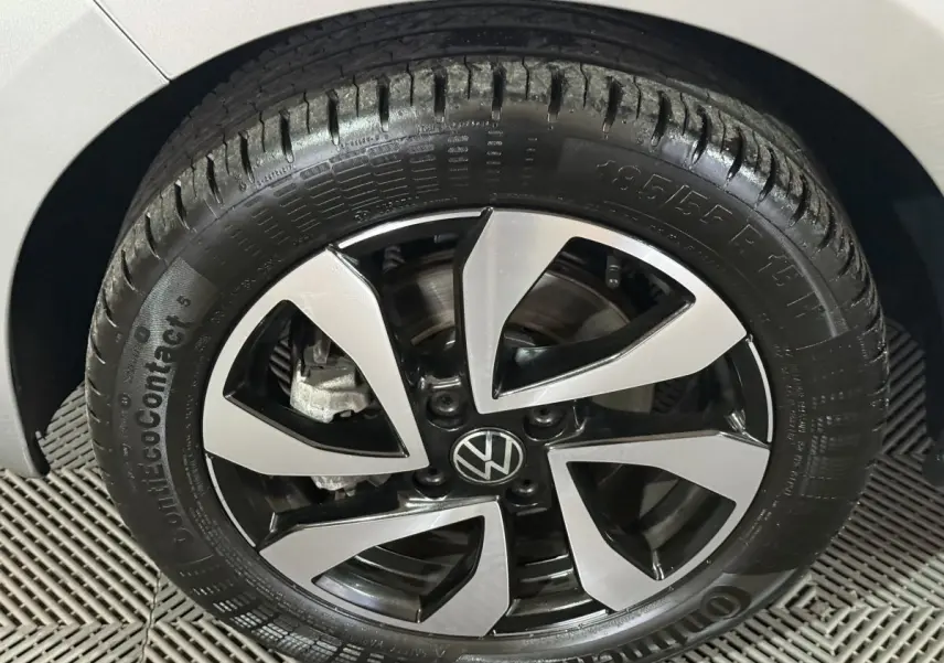 Gros plan sur la roue avant droite d'une Volkswagen Up gris foncé avec jante alliage bicolore et logo VW central.