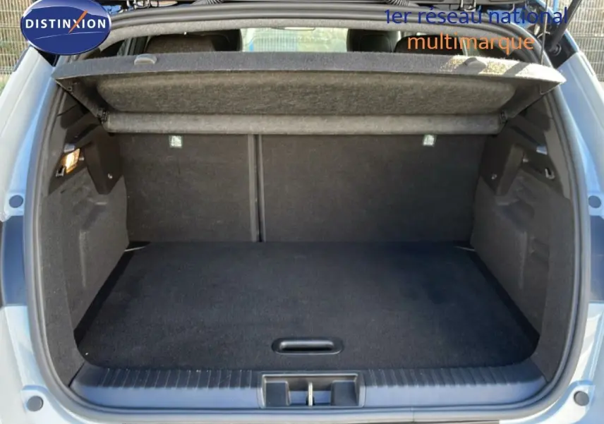 Coffre ouvert vu de l'arrière d'un Renault Captur 2025 gris Rafale métal avec toit noir, espace de chargement vide et tapis noir.