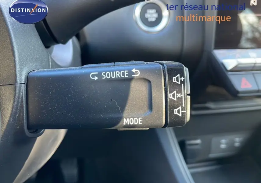 Gros plan sur la commande audio au volant d'un Renault Captur gris Rafale métal avec toit noir, intérieur moderne.