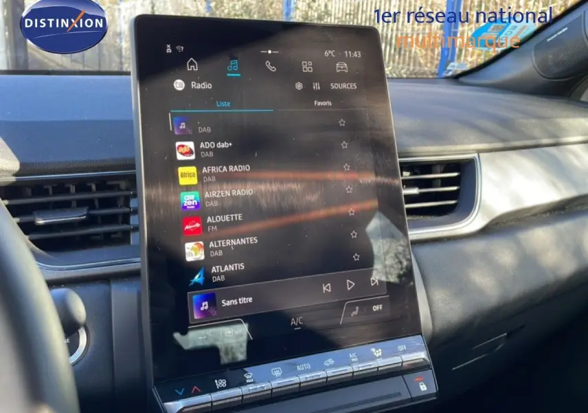 Vue intérieure du tableau de bord du Renault Captur 2025, écran tactile central affichant les radios DAB, ambiance grise et noire.