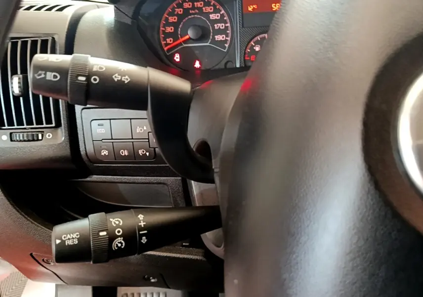 Gros plan sur le volant noir et les commandes de clignotants du tableau de bord du Fiat Ducato Fourgon blanc de 2021.
