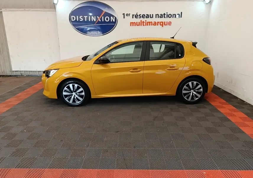 Peugeot 208 jaune vue de profil côté gauche dans un showroom avec sol gris et bandes rouges.