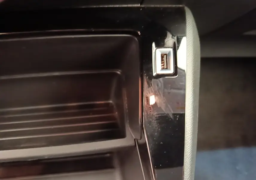 Gros plan sur la prise USB dans le rangement central intérieur de la Peugeot 208 jaune PureTech 75 S&S Active Pack 2023.