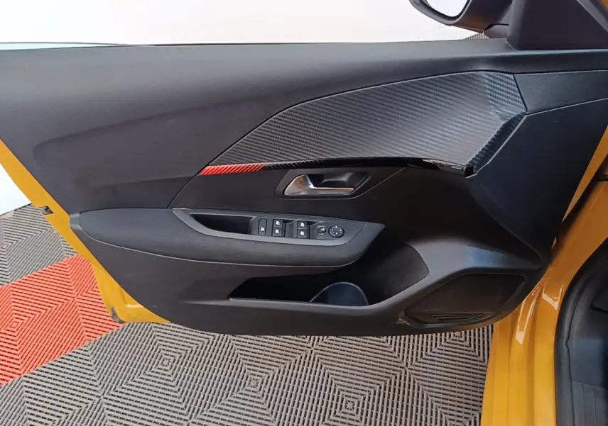 Vue rapprochée de la porte avant gauche jaune d'une Peugeot 208 2023, avec commandes électriques et insert décoratif noir.