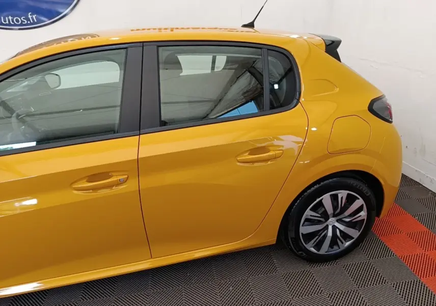 Vue latérale droite d'une Peugeot 208 jaune 2023 avec jantes alliage et poignées de porte ton caisse.