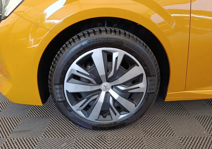 Gros plan sur la roue avant gauche de la Peugeot 208 jaune, mettant en valeur la jante design et la carrosserie brillante.