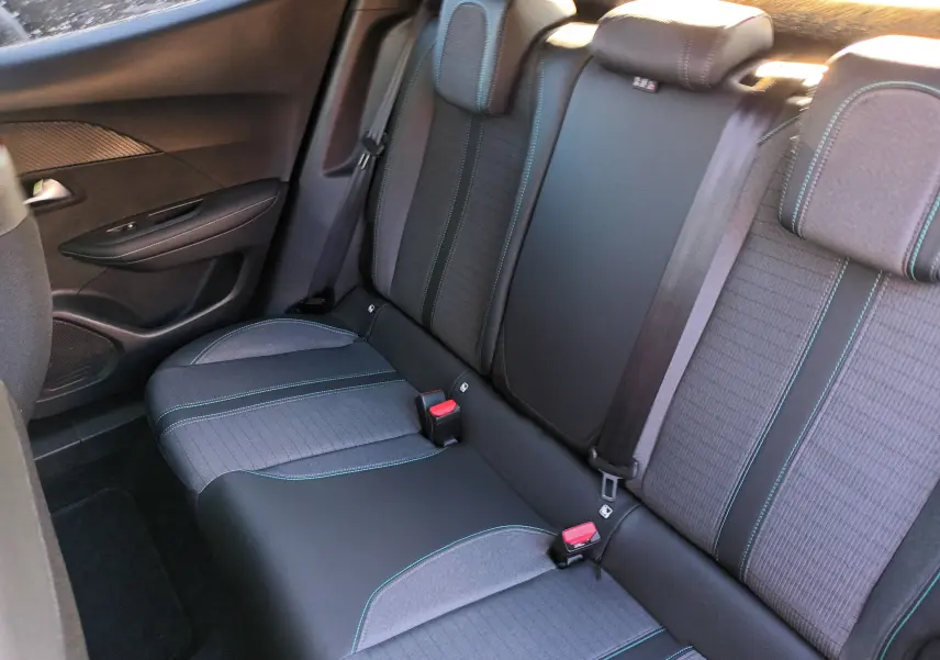 Vue intérieure arrière des sièges arrière en tissu gris et noir avec surpiqûres bleues d'un Peugeot 2008 noir 2022.
