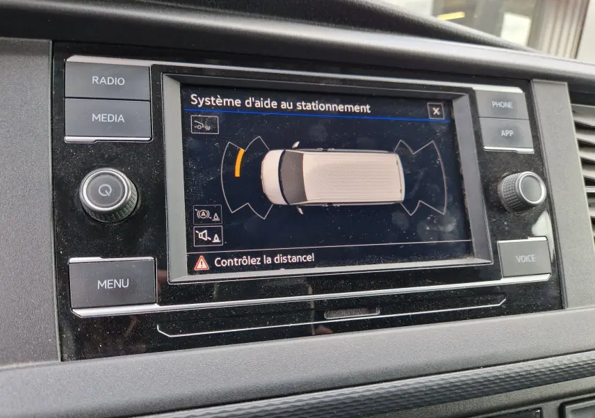 Écran central du Volkswagen Transporter 2020 montrant l'aide au stationnement avec interface tactile et boutons autour.