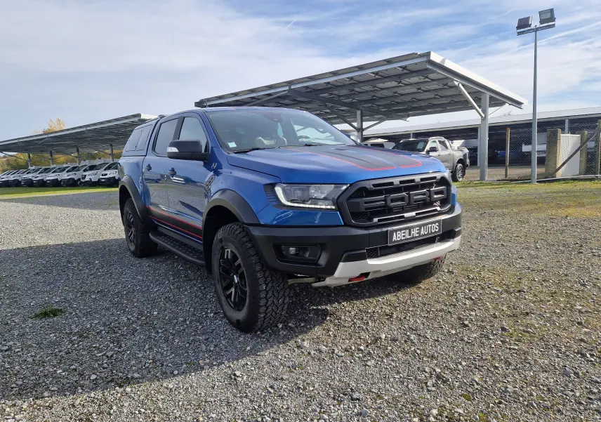 Ford Ranger Raptor bleu Ford Performance vu en 3/4 avant droit, avec hard top et marquages rouges sur capot et flancs.