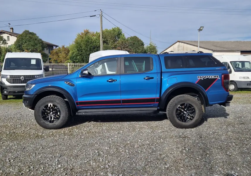 Vue de profil côté gauche d'un Ford Ranger Raptor bleu Ford Performance avec hard top noir et jantes noires.