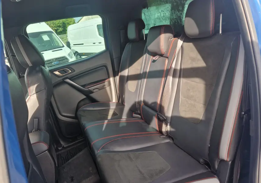 Vue intérieure côté droit du Ford Ranger Raptor 2022, sièges arrière en cuir noir avec surpiqûres rouges.