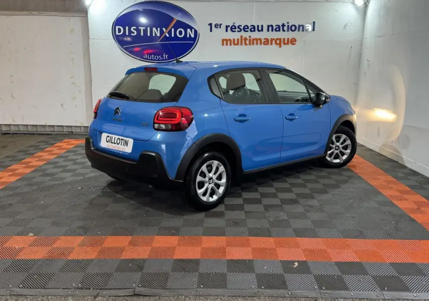 Citroën C3 bleu en 3/4 arrière droit dans un showroom avec logo Distinxion en arrière-plan.