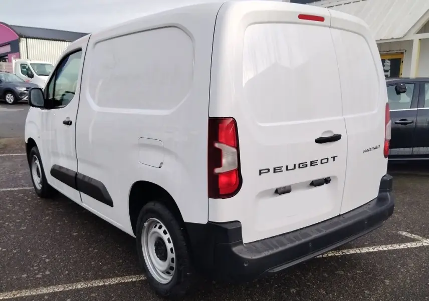 Vue 3/4 arrière droite d’un Peugeot Partner Fourgon blanc Icy avec portes arrière pleines et protections noires sur les flancs.
