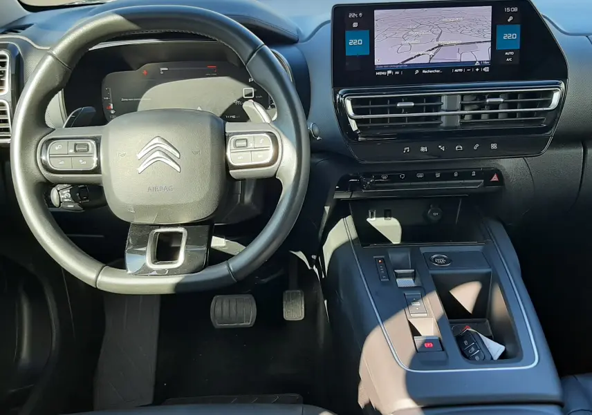 Vue intérieure du poste de conduite du Citroën C5 Aircross 2024, tableau de bord noir avec écran tactile et volant multifonction.