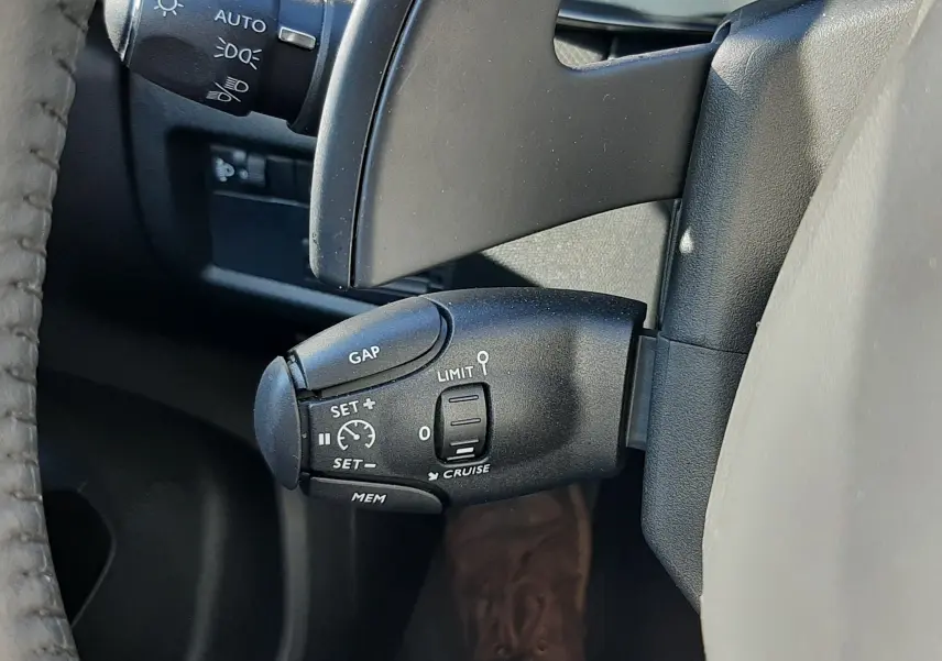 Gros plan sur la commande de régulateur de vitesse à gauche du volant d’un Citroën C5 Aircross 2024 noir Perla Nera.