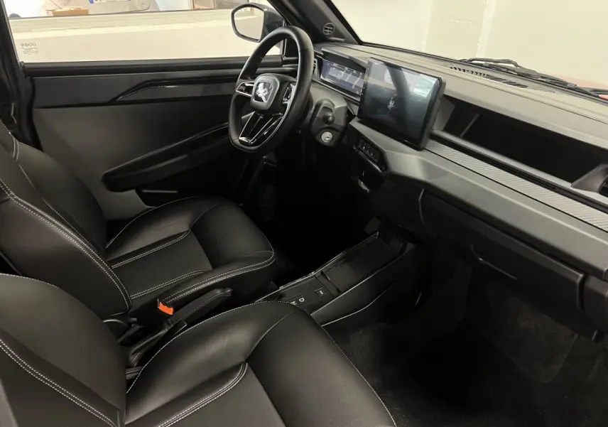 Vue intérieure avant droite de la LIGIER JS50 BEV 8KWH ELITE 2025 avec sièges noirs et écran tactile central.