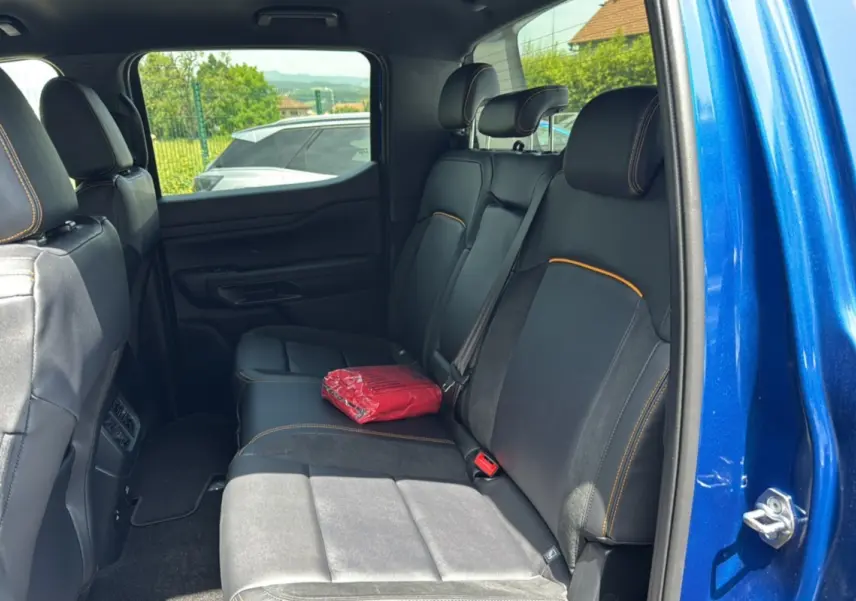 Vue intérieure côté droit sur la banquette arrière en cuir noir avec surpiqûres orange du Ford Ranger bleu lightning.