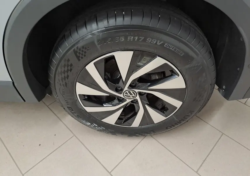 Gros plan sur la roue avant droite du Volkswagen Tiguan 2.0 TDI 150 DSG7 VW Edition avec jante alu bicolore et carrosserie argent Dolomite.