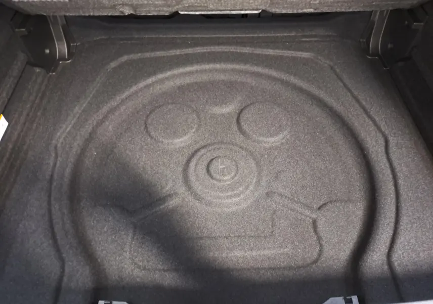 Coffre ouvert du Volkswagen Tiguan 2025, vue plongeante sur l’espace de rangement avec tapis de sol gris foncé.