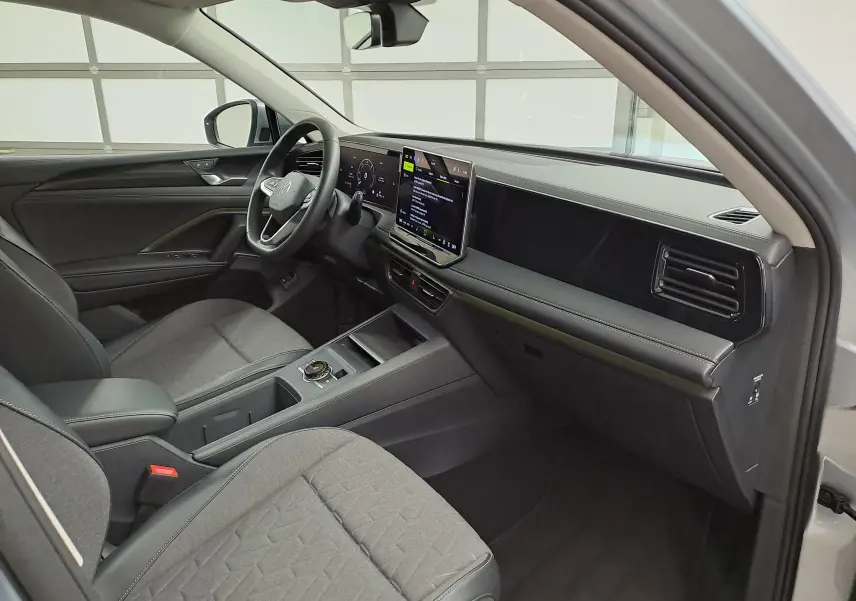 Vue intérieure côté conducteur du Volkswagen Tiguan 2025 avec tableau de bord moderne et sièges tissu gris.