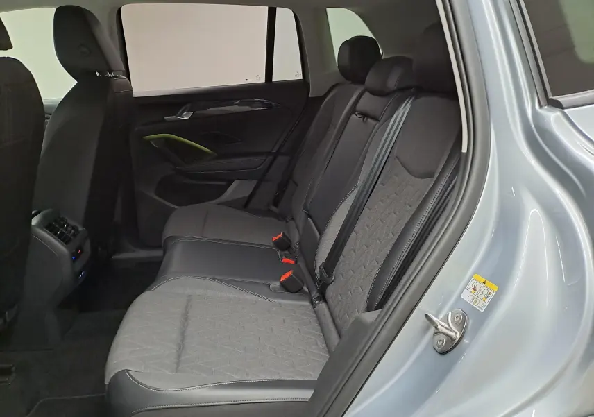 Vue intérieure côté droit des sièges arrière du Volkswagen Tiguan 2025 en Argent Dolomite avec sellerie tissu et cuir.