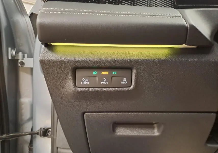 Détail du tableau de bord côté gauche du Volkswagen Tiguan 2025 Argent Dolomite avec commandes d'éclairage et bandeau lumineux jaune.
