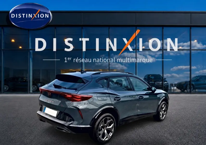 Vue 3/4 arrière droite d'une CUPRA Formentor 1.5 etsi hybrid bleu fjord avec jantes 18 pouces devant un showroom Distinxion.