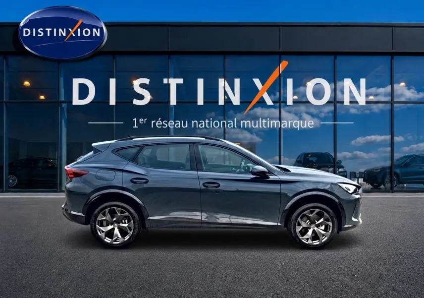 Vue latérale droite d'un CUPRA Formentor 1.5 etsi hybrid bleu fjord garé devant une vitrine avec logo Distinxion.