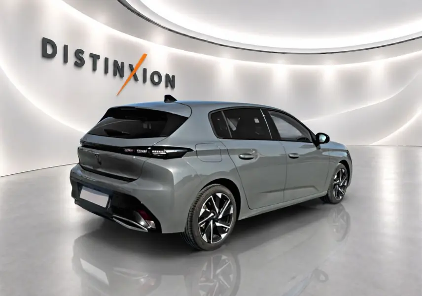 Peugeot 308 gris en vue 3/4 arrière droit, jantes alliage noires et vitres arrière surteintées dans un studio lumineux.