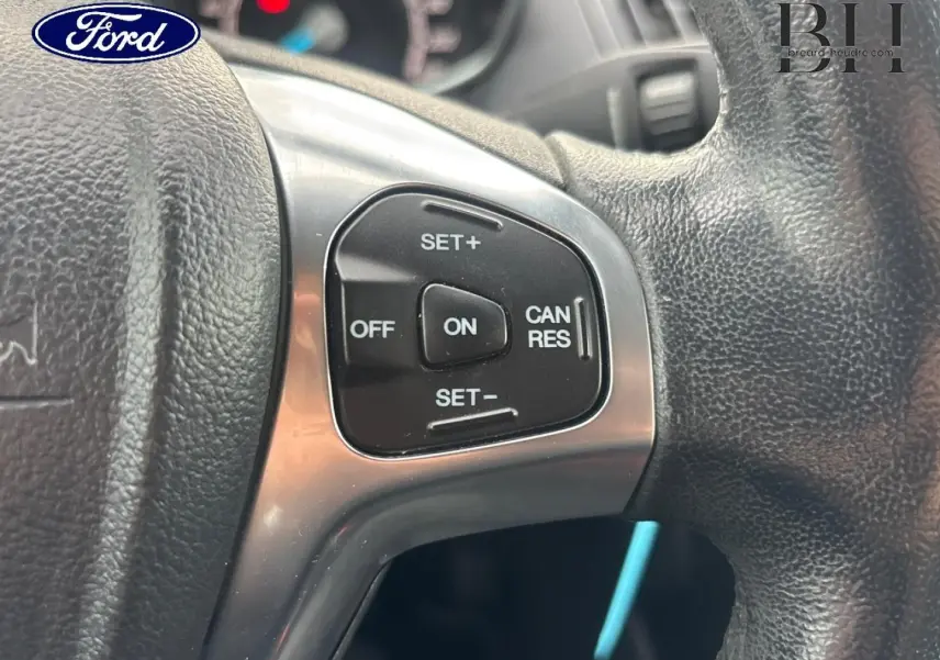 Gros plan sur les commandes du régulateur de vitesse au volant cuir d'une Ford B-MAX rouge Premium Candy.