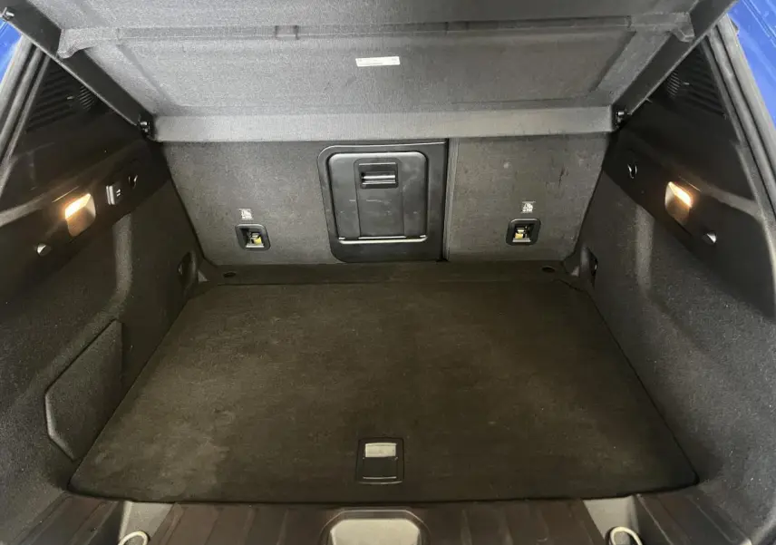 Coffre ouvert de l'Alfa Romeo Tonale bleu 2024, montrant un espace de chargement propre et éclairé.