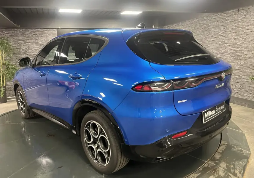 Vue 3/4 arrière droite d'un Alfa Romeo Tonale bleu métallisé avec jantes en alliage et feux arrière LED distinctifs.