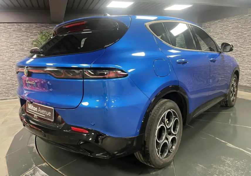 Vue 3/4 arrière droite de l'Alfa Romeo Tonale bleu métallisé avec jantes alliage et diffuseur noir brillant.