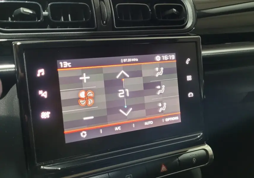 Écran tactile central affichant la climatisation à 21°C dans l'habitacle noir d'une Citroën C3 beige 2022.