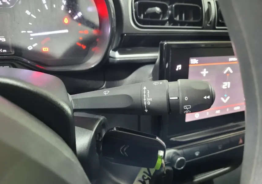 Gros plan sur la manette d'essuie-glace et le tableau de bord noir de la Citroën C3 beige 2022, écran tactile visible.
