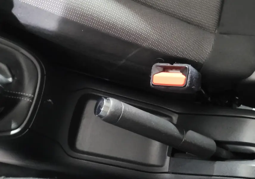 Gros plan sur le frein à main et la ceinture de sécurité côté conducteur dans l'habitacle d'une Citroën C3 beige.