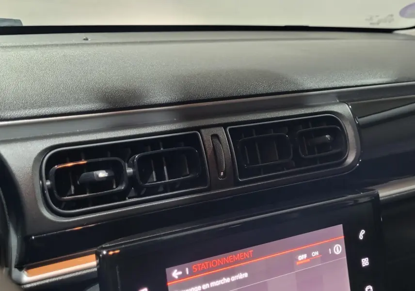 Gros plan sur la console centrale noire et les aérateurs du tableau de bord d'une Citroën C3 beige de 2022.