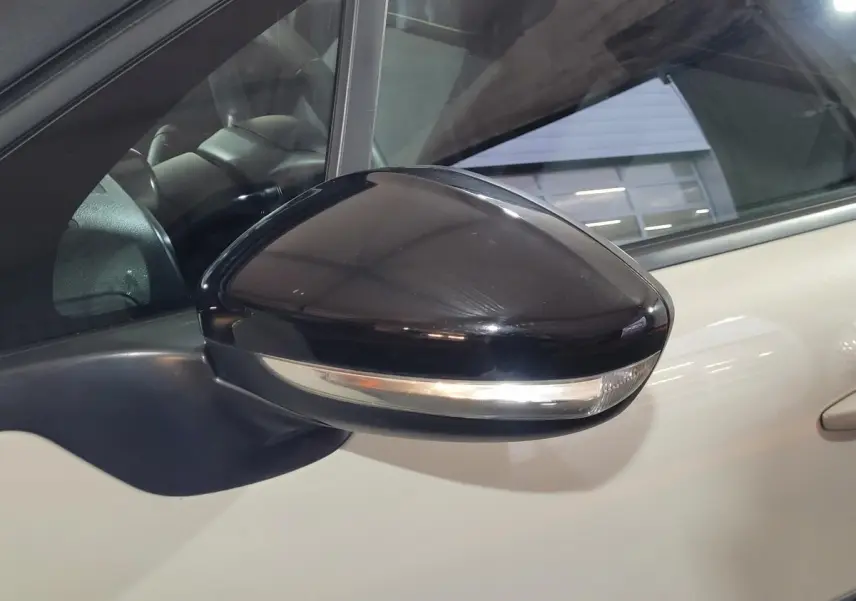 Rétroviseur noir avec clignotant intégré sur le côté gauche d'une Citroën C3 beige 2022.