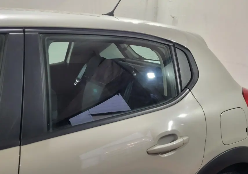 Vue latérale côté gauche sur l'arrière d'une Citroën C3 beige avec poignée de porte et réservoir visible.
