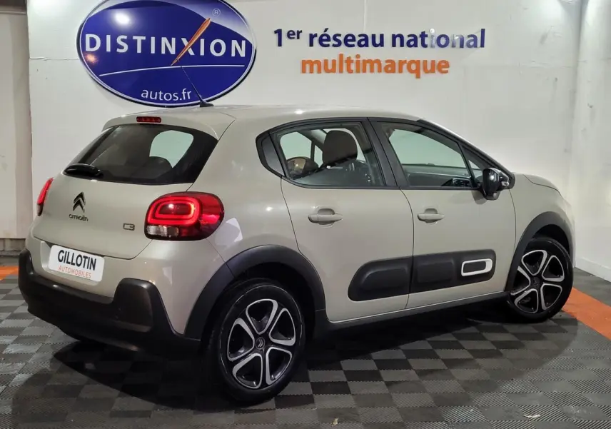Citroën C3 beige vue 3/4 arrière droit, avec protections latérales noires et jantes alliage distinctives.