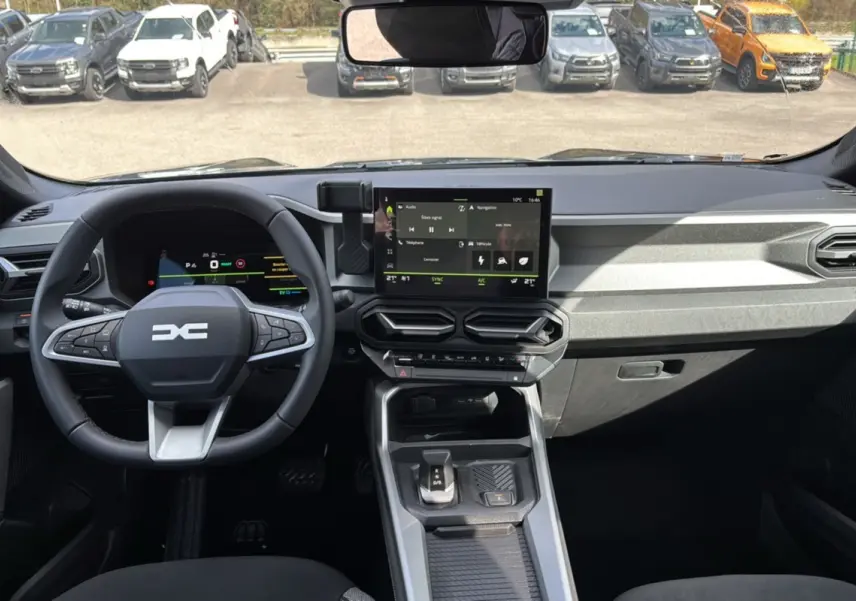 Vue intérieure avant du tableau de bord du Dacia Bigster Hybrid 155 avec écran tactile et volant cuir noir.