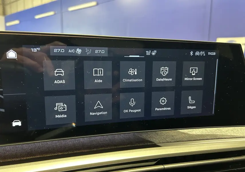 Écran tactile central du Peugeot 3008 Hybrid 2025 affichant les menus de climatisation, navigation et aides à la conduite.