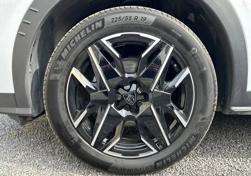 Gros plan sur la jante avant droite noire et argentée du Peugeot 3008 blanc Okenite, équipée de pneus Michelin 225/55 R19.
