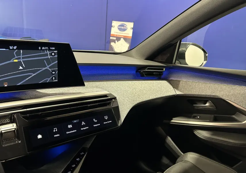 Vue intérieure côté passager du tableau de bord du Peugeot 3008 blanc Okenite 2025 avec éclairage d'ambiance bleu et écran tactile.
