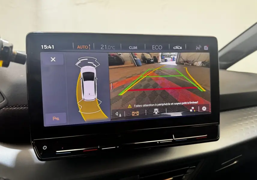 Écran tactile central du CUPRA Born 2023 montrant l’aide au stationnement avec vue caméra arrière et alertes.