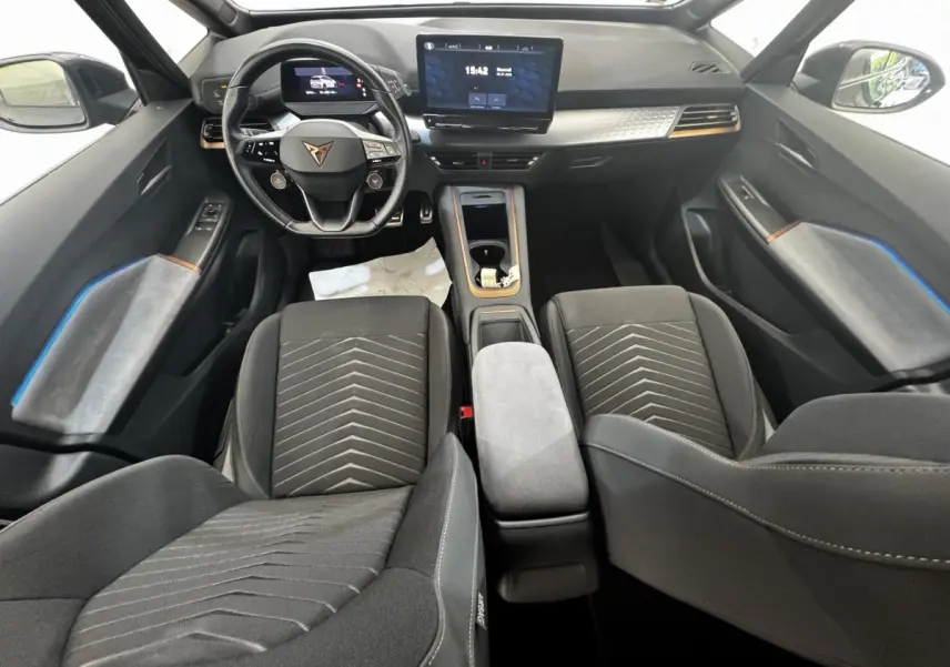 Intérieur avant du CUPRA BORN gris foncé 2023, vue du tableau de bord avec volant multifonctions et écran tactile central.